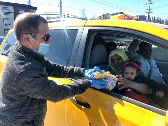 Monzur Choudhury hands out goodie bags to a local family on Sunday. Within the first hour of the Eid event, over 40 cars had driven by to pass along holiday greetings and collect the treats. (Danielle d'Entremont/CBC)